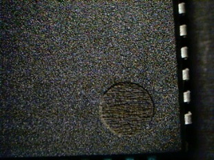 A dark grey counterfeit part is showing with what a circle that looks a bit like an indent but is not
